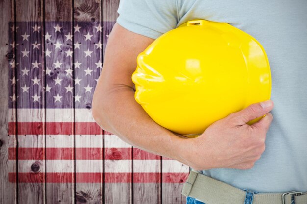 Composite image of technician holding hard hat