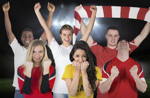 Composite image of various football fans against football pitch under spotlights