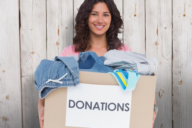 Composite image of volunteer holding clothes donation box