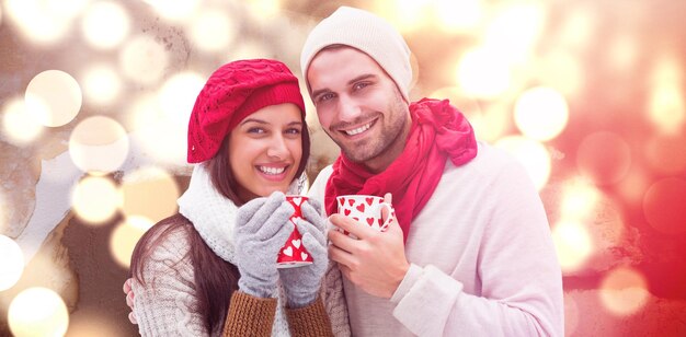 Composite image of winter couple holding mugs