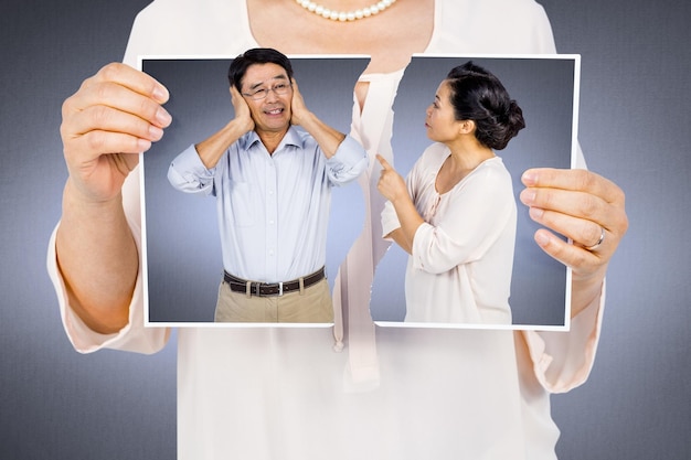 Composite image of woman holding a torn photo