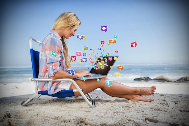 Foto immagine composita della donna che si siede sulla spiaggia usando il suo computer portatile 3d