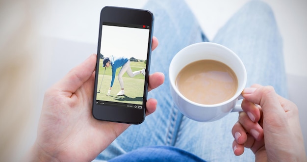 Composite image of woman using her mobile phone and holding cup of coffee