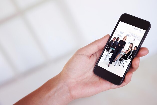 Composite image of womans hand holding black smartphone