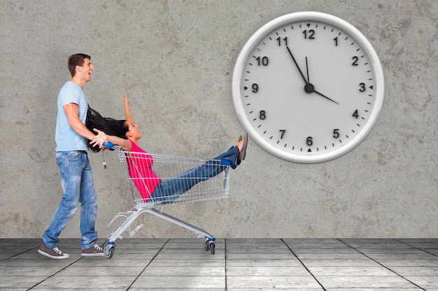 Composite image of young couple having fun with shopping cart