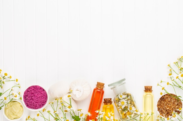 Composition aromatherapy with natural cosmetics and chamomile flowers on light background