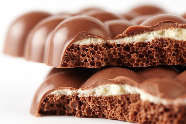 Composition of bars and pieces of porous milk chocolate with a\
coconut layer closeup on a white background isolated