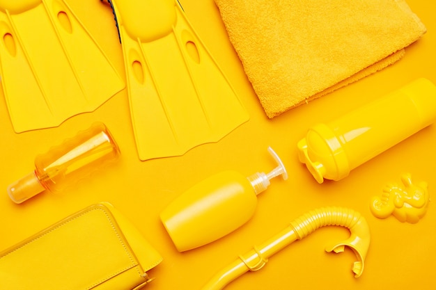 Composition of beachwear and accessories on a yellow