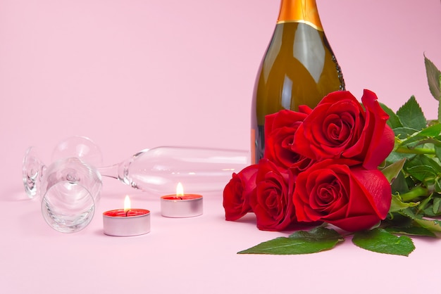 Una composizione di un bellissimo bouquet di rose, candele, bicchieri e una bottiglia di champagne crea una carta romantica. il concetto di san valentino, festa della mamma, 8 marzo.