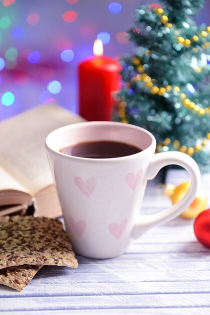 Photo composition of book with cup of coffee and christmas decorations on table on bright background