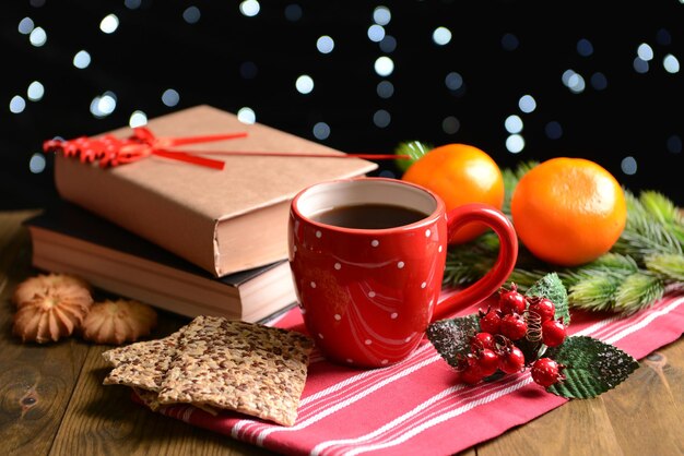 Composizione del libro con una tazza di caffè e decorazioni natalizie sul tavolo su sfondo scuro