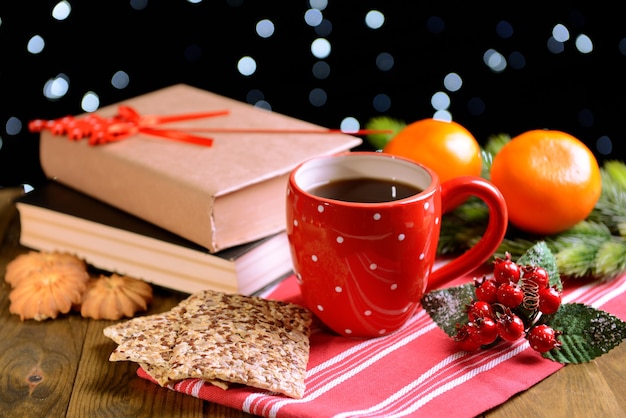 Composition of book with cup of coffee and Christmas decorations on table on dark wall