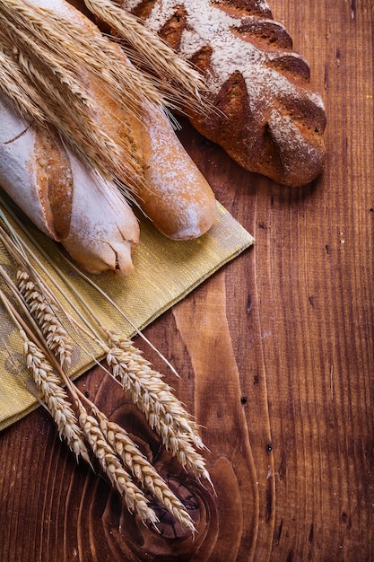 Composition of bread and wheat ears on old wooden boards