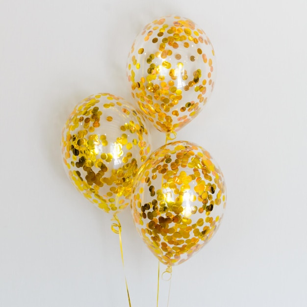 Composition of bright gold confetti balloons on white background Golden gift for boys and girls