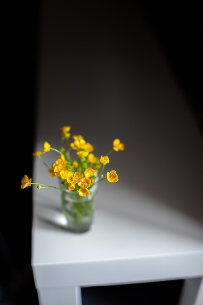 Composition of bright yellow wild flowers in a glass beaker