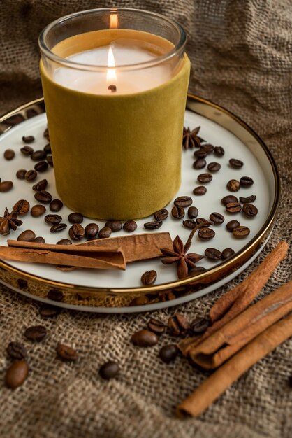 Composition of candles and spices on a platter, on a background of burlap