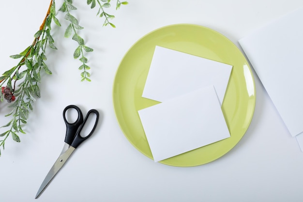 Composition of cards with copy space on green plate, scissors and branches on white background. christmas, communication, tradition and celebration concept