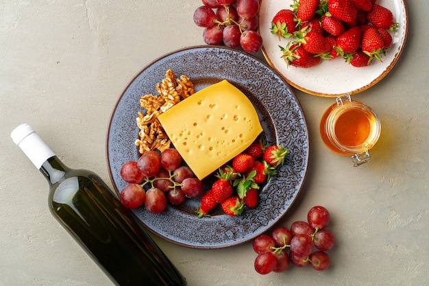 Composition of cheese, and fruits on gray table wall