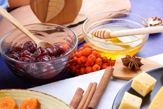 Состав сыра с орехами, ягодами и фруктами на черной тарелке Сыр с медом на бело-голубом фоне крупным планом