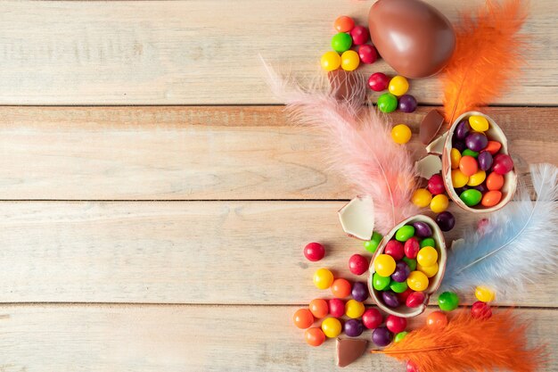 Composition of chocolate Easter eggs and delicate feathers on a light background 