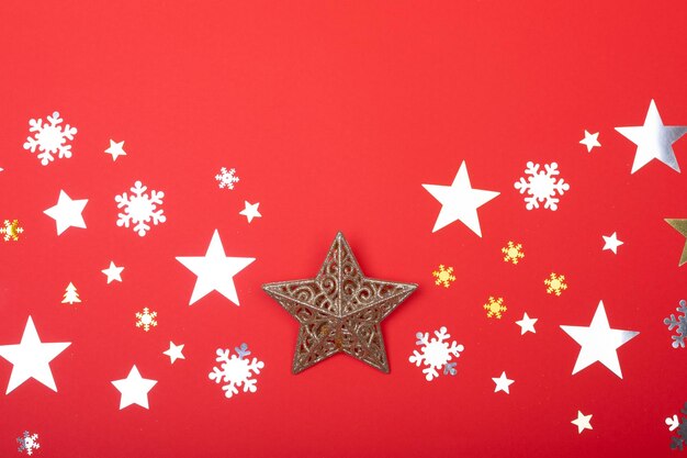 Composizione di decorazioni natalizie con stelle, fiocchi di neve e spazio copia su sfondo rosso. concetto di natale, tradizione e celebrazione.