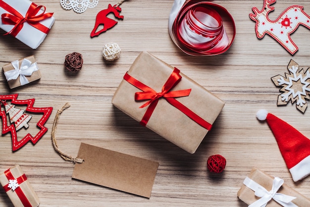 Photo composition of christmas tree toys, ribbons and decorated gift boxes on rustic wooden table.