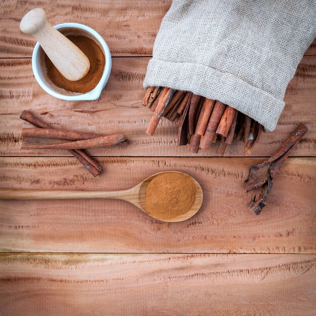 Composition of cinnamon stick and powder on wooden background .