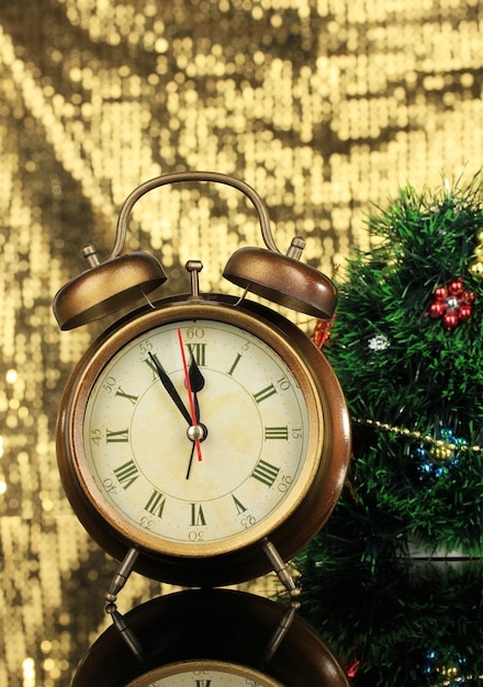 Composition of clock and christmas decorations on bright surface