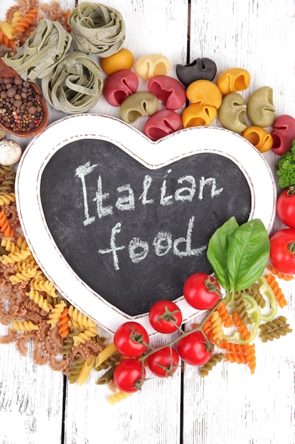 Composition of colorful pasta fresh tomatoesbasil on wooden background