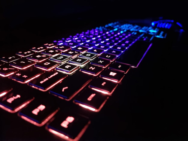 Composition of computer and mouse with neon in dark background