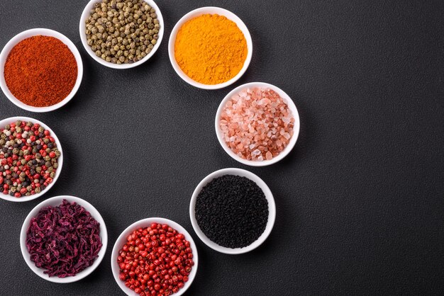 Composition consisting of a variation of several types of spices in white ceramic bowls on a textured concrete background