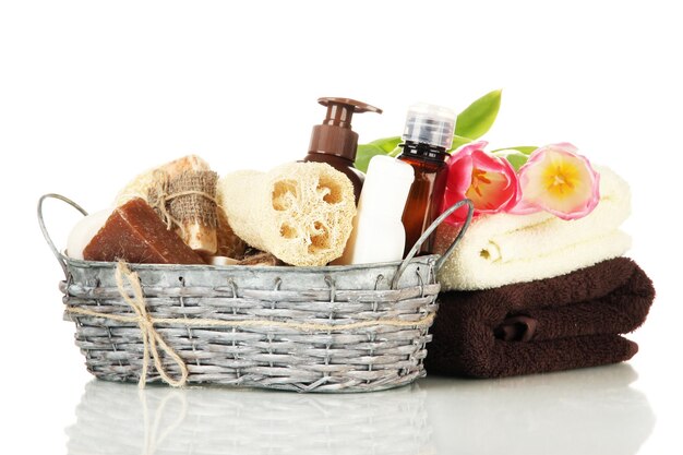 Photo composition of cosmetic bottles and soap in basket isolated on white