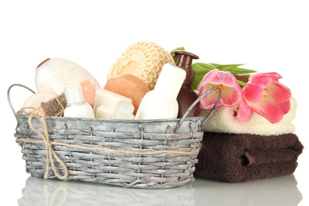 Photo composition of cosmetic bottles and soap in basket isolated on white