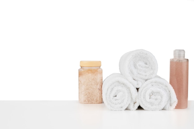 Composition of cosmetic bottles and towels isolated on white