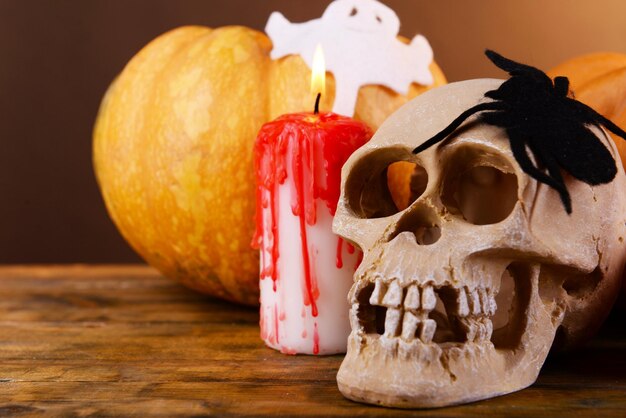 Композиция из декоративных тыквенных свечей черепа и украшений Хэллоуина на деревянном столе на темном фоне