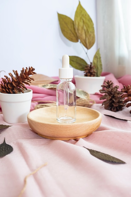 La composizione mostra il prodotto. bottiglia trasparente per la cura della pelle con sfondo di foglie secche naturali. composizione minimalista con prodotti