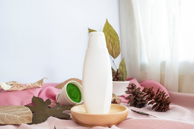 The composition displays the product. white cosmetic bottle with natural dried leaves decoration. minimalist composition featuring products