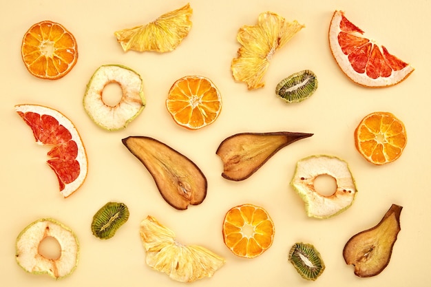 Composition of dried fruits (kiwi, pear, mandarin, orange, grapefruit, apple) on colored . Dried fruits top view