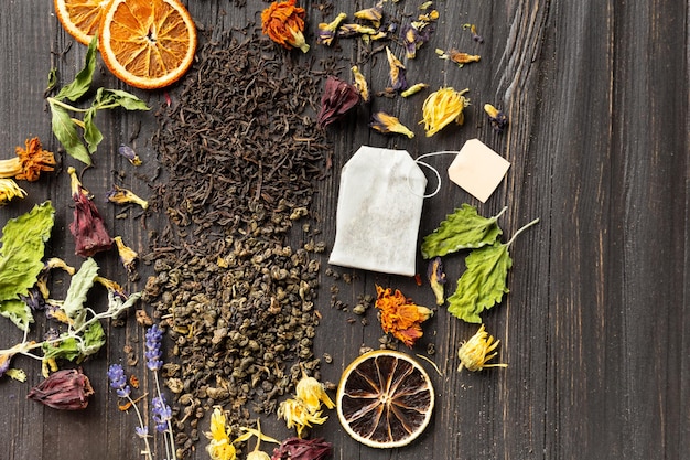 Composition of dry black and green tea tea bag dried citrus slices and dry hibiscus flowers on a dark wooden background top view Different types of dry tea on a dark background