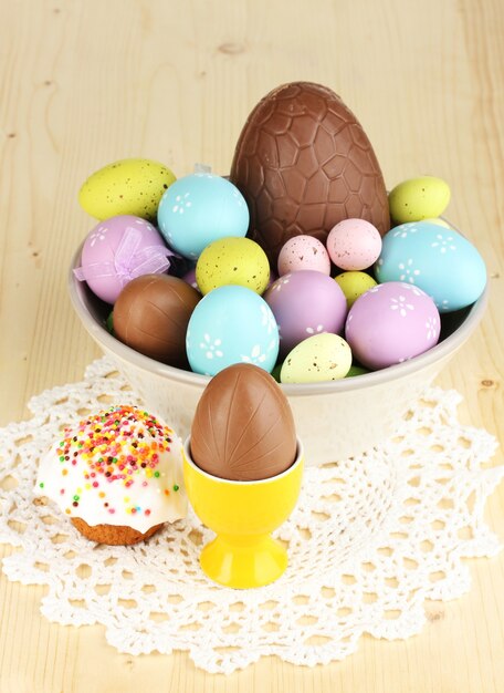 Composition of Easter and chocolate eggs and simnel on wooden table close-up