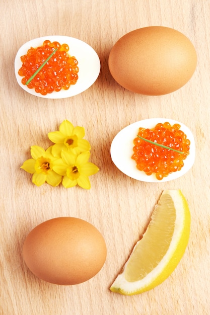 a composition of eggs and red caviar and flowers over natural background