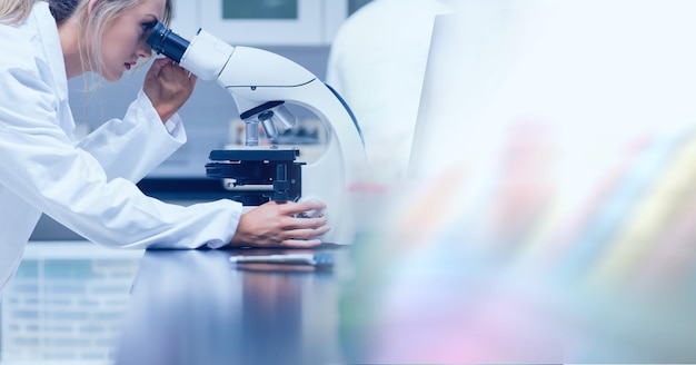 Composition of female lab technician using microscope, with blurred copy space to right