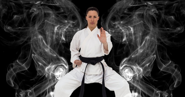 Composition of female martial artist over trails of smoke on black background