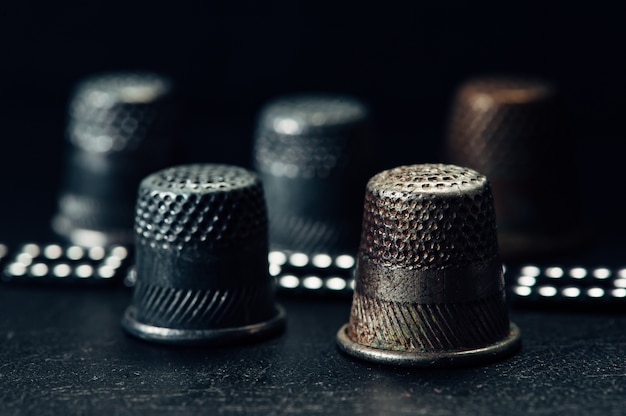 Composition of few old thimbles on black surface in macro