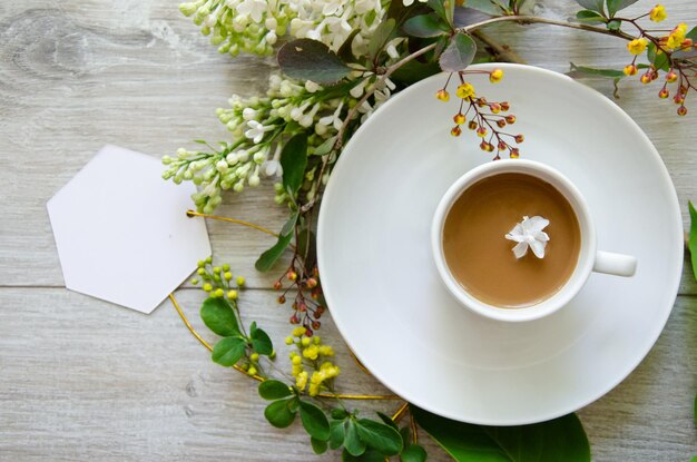 Composition flatlay with an coffee cup on a saucer with mockup an empty white card