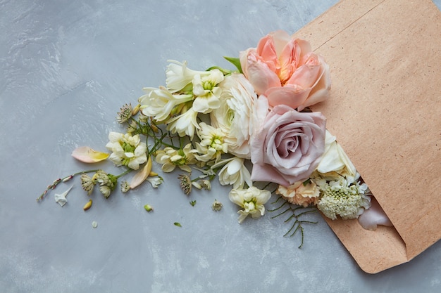 Composition of flowers represented in envelope on grey background. Bouquet for woman from man in Valentine's Day. Roses with different flowers. Holiday concept.