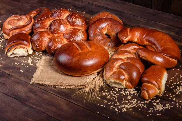 Composition of fresh baked sweet buns with poppy and jam. Sweet baking laid out as a composition on a wooden table