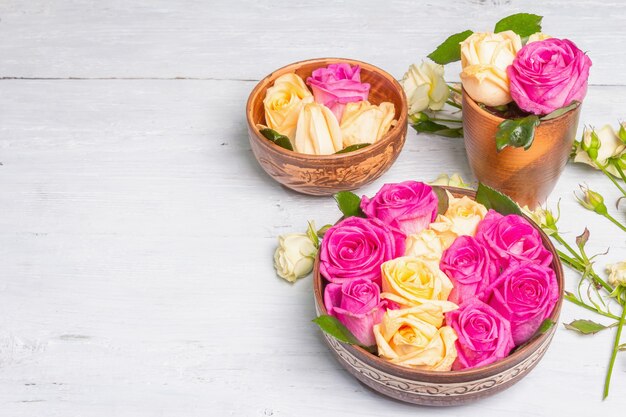 Composition of fresh multicolored roses in kitchen utensil. The festive concept for Weddings, Birthdays, March 8th, Mother's, or Valentine's Day. Greeting card, flat lay, old wooden table