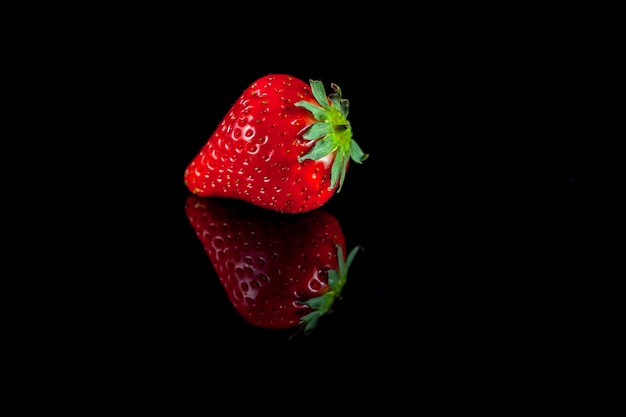 Composition of fresh strawberries on a black background with reflection