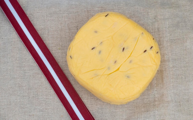 Composition from ribbon of national flag and caraway cheese on linen fabric bannerLatvia